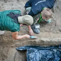 Archeolodzy prowadzą ekshumację, ostrożnie badając warstwy ziemi.