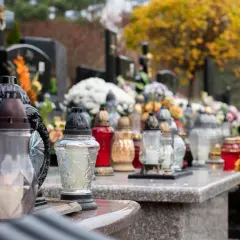 Znicze i kwiaty na grobach, jesienne liście. Kto sprząta wieńce po pogrzebie? Pamięć trwa.