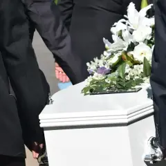 Biała trumna z kwiatami niesiona przez żałobników. Zastanawiasz się, ile kosztuje trumna?