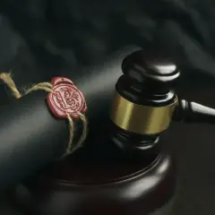Sądowy młotek i zapieczętowany dokument, symbolizujące formalności związane ze spadkiem po zmarłym.
