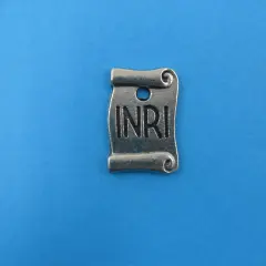 Metalowy zwój z napisem INRI, symbolizujący tabliczkę z krzyża.