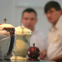 Trzy urny pogrzebowe z krzyżami, w tle niewyraźne postacie. Temat kremacji budzi dyskusje, nawet wśród hierarchów Kościoła, jak papież o kremacji.