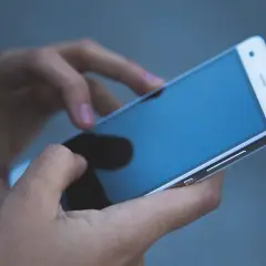 Dłonie trzymają telefon zmarłej osoby, przeglądając ostatnie wiadomości.