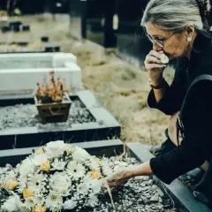 Kobieta w żałobie klęczy przy grobie, ocierając łzy. Kto to dysponent? Może osoba, która zorganizowała ten smutny dzień.