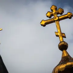 Złoty krzyż prawosławny na tle nieba. Drugi krzyż prawosławny widoczny w oddali.