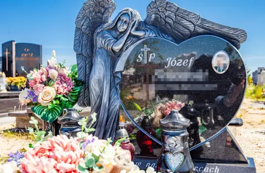 Kamienna anielica czuwa nad sercem z granitu, na którym widnieją krótkie sentencje na pomnik. Kwiaty i znicze zdobią grób.