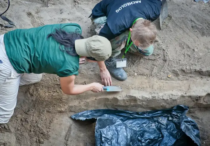 Archeolodzy prowadzą ekshumację, ostrożnie badając warstwy ziemi.