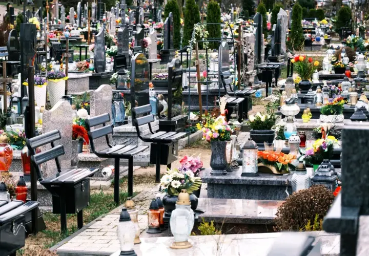 Ławki na cmentarzu, przygotowane na wizytę bliskich. Wiele zniczy i kwiatów świadczy o pamięci.