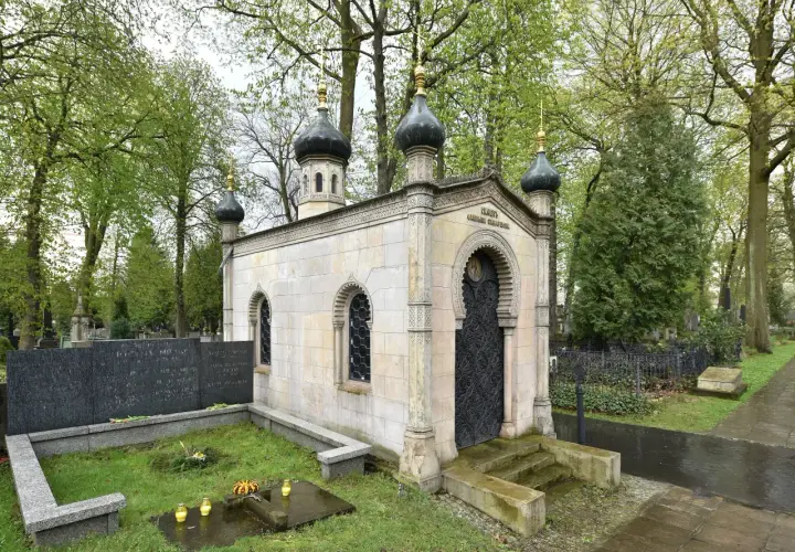 Imponujący grobowiec na cmentarzu, przypominający małą cerkiew, z charakterystycznymi kopułami i bogato zdobionymi drzwiami.