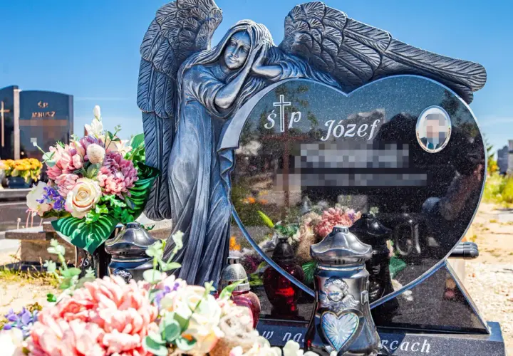 Kamienna anielica czuwa nad sercem z granitu, na którym widnieją krótkie sentencje na pomnik. Kwiaty i znicze zdobią grób.
