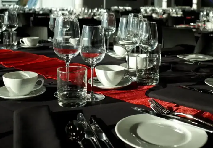 Elegancko nakryty stół na stypę, z kieliszkami do wina i szklankami, sugeruje, że alkohol może być serwowany.