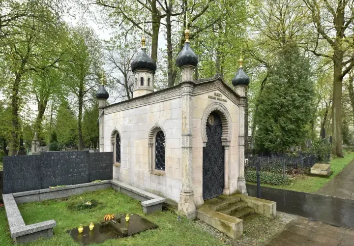Kamienna kaplica z kopułami, ozdobnymi oknami i drzwiami, stanowi piękny grob.
