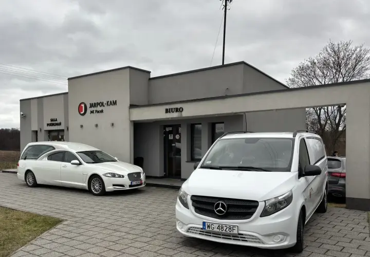 Przed budynkiem "JARPOL-KAM" stoją karawan i van. Firma zajmuje się transportem zmarłych, odpowiadając na pytanie, kto pokrywa koszty sprowadzenia zwłok z zagranicy.