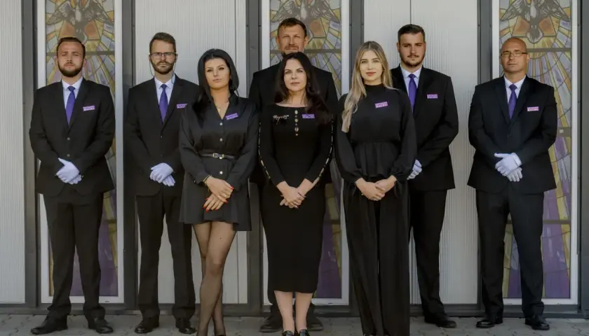 Zespół w czarnych strojach przed witrażem. Jeśli chcesz dowiedzieć się, jak sprawdzić datę pogrzebu, skontaktuj się z nimi.