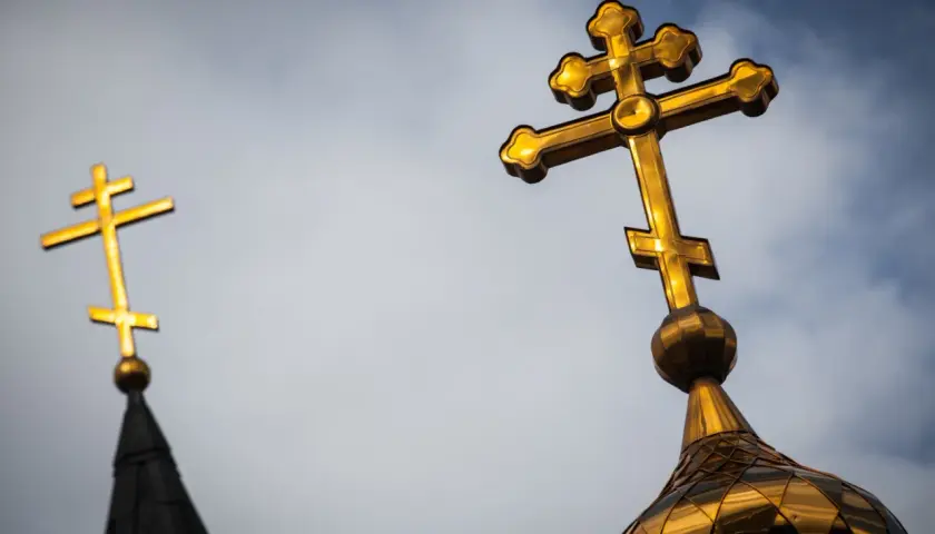 Złoty krzyż prawosławny na tle nieba. Drugi krzyż prawosławny widoczny w oddali.