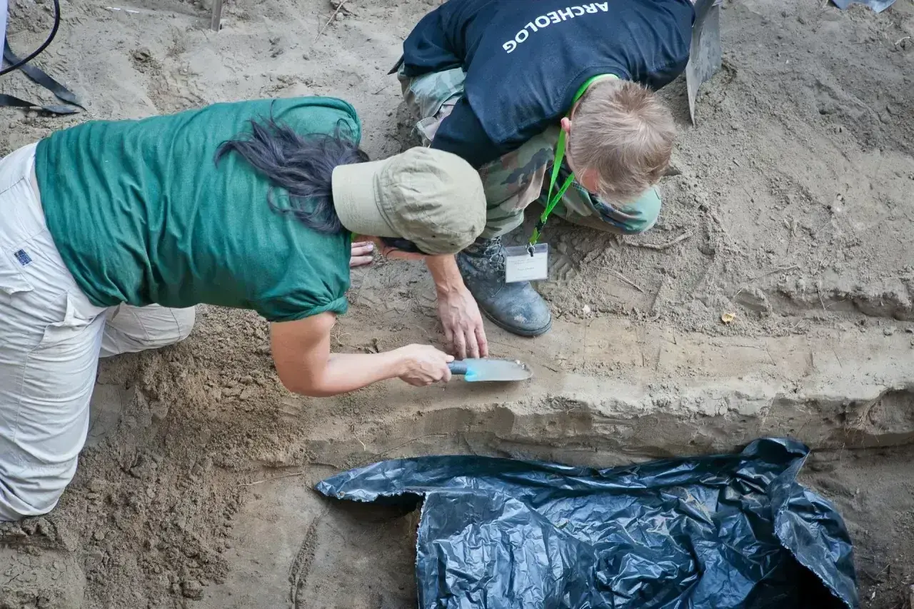 Archeolodzy prowadzą ekshumację, ostrożnie badając warstwy ziemi.