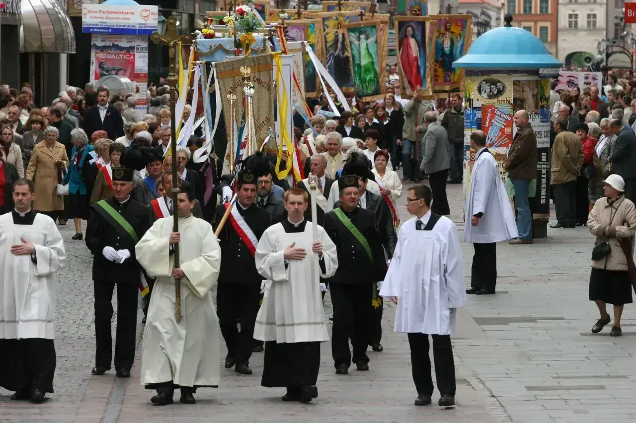 Procesja religijna z chorągwiami i duchownymi w strojach. Długość mszy świętej może być różna, ale ta uroczystość trwa.