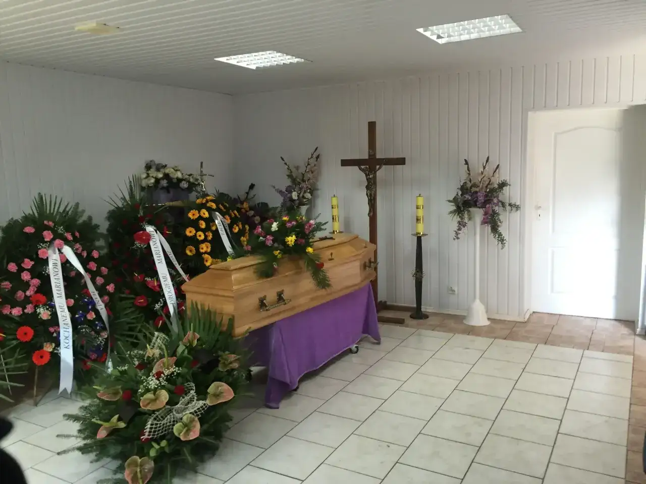 Piękne kwiaty na trumnę, wieńce pogrzebowe i krzyż tworzą smutną, ale pełną szacunku atmosferę.