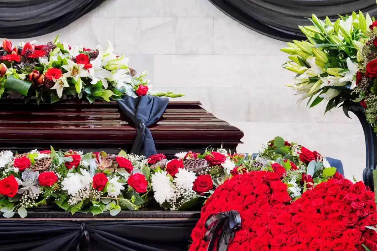 Trumna ozdobiona wieńcami z czerwonych róż i białych lilii. Kto sprząta wieńce po pogrzebie?